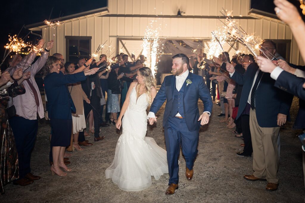 Enchanting Exit: Guests Waving Sparklers as Bride and Groom Depart with Dry Ice Sparklers in the Background - A fairytale ending to a perfect day