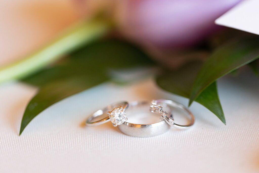 Artfully arranged flat lay capturing the gleaming brilliance of the groom's gold wedding band alongside the bride's sparkling diamond ring.