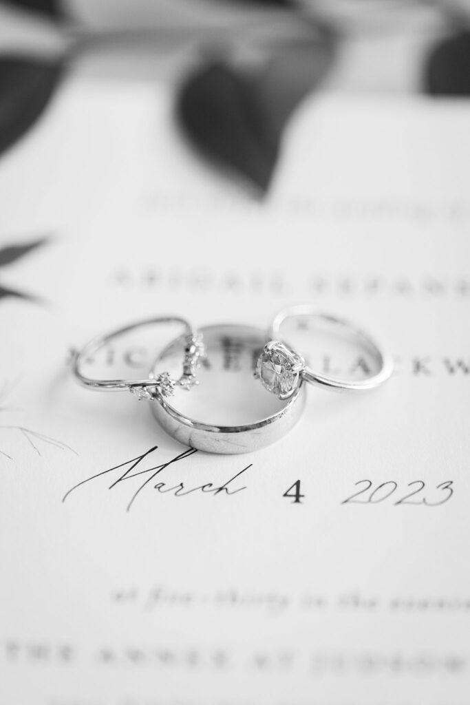 Close-up of bride's diamond engagement ring and wedding band resting on a lace-detailed flat lay
