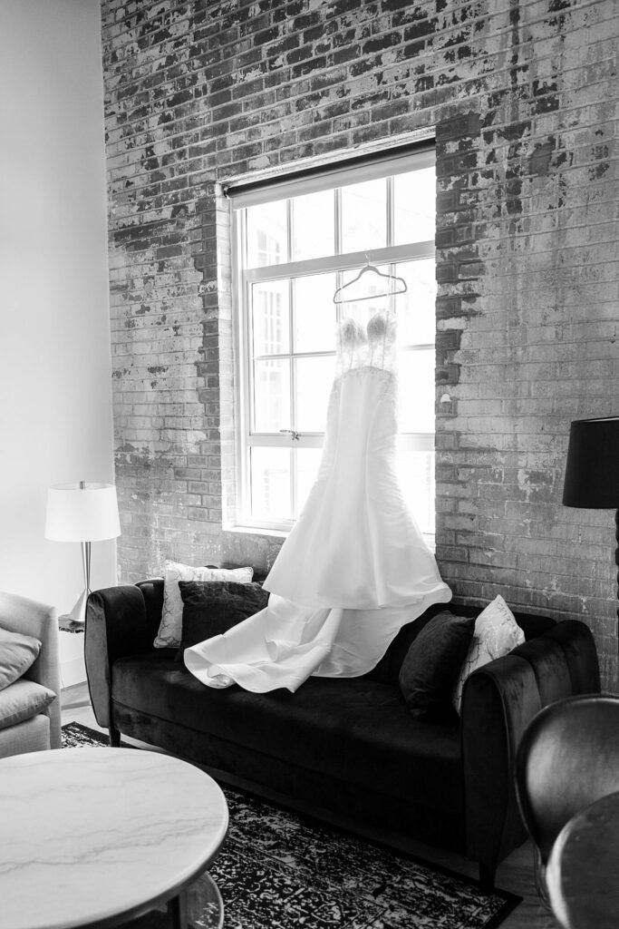 Elegant lace wedding dress hanging on a rustic wooden hanger