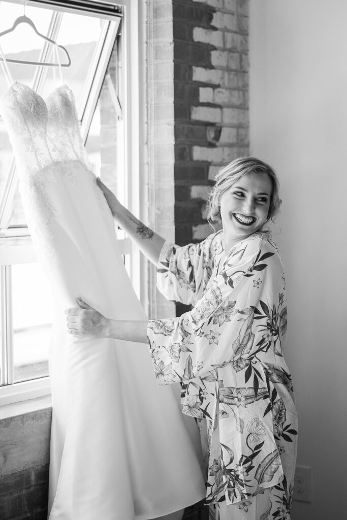 With utmost care, the bride's train is gracefully arranged by her loved ones, ensuring every detail is perfect for her big day at Judson Mill, downtown Greenville, South Carolina.