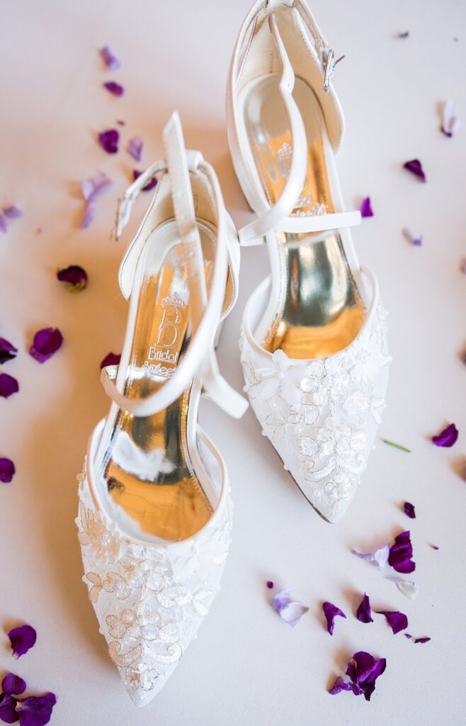 Elegant white bridal flatlays featuring delicate lace wedding shoes on a rustic wooden background at Judson Mill, Greenville, South Carolina