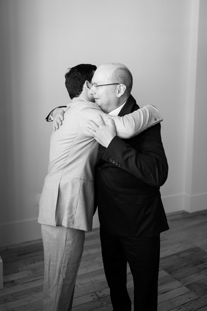 A beautiful display of paternal love as the groom's father affectionately hugs him, encapsulating the deep bond and joyous connection between father and son on this momentous occasion.