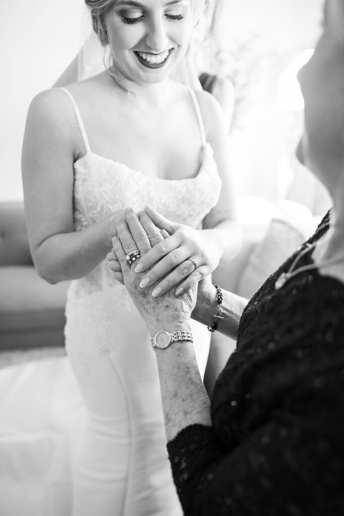 Heartwarming moment captured as the bride's mother delicately fastens the buttons of her intricately detailed wedding gown at Judson Mill, downtown Greenville.