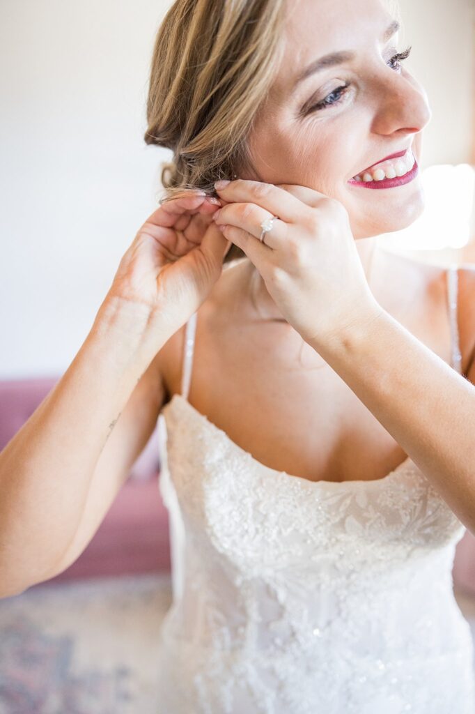 A tender moment freezes in time as the bride gently adjusts her earrings, capturing her attention to detail and elegance.