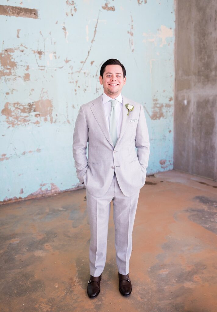 Captured in a stunning close-up, the groom exudes confidence and charm, showcasing his impeccable style and rugged good looks at the picturesque Judson Mill wedding venue in Greenville, South Carolina.