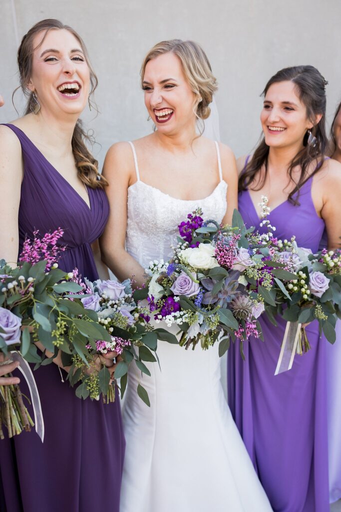 A heartfelt moment captured as the bride shares a laugh with her bridesmaids at Judson Mill wedding in downtown Greenville.