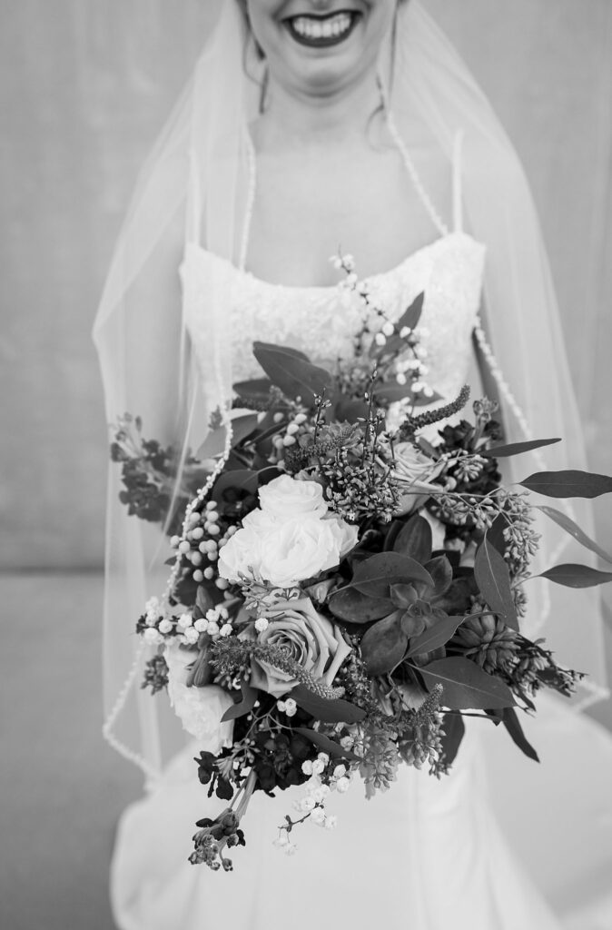 Exquisite bride mesmerizes with her bridal bouquet, embodying pure elegance amidst the industrial charm of Judson Mill in downtown Greenville, South Carolina.