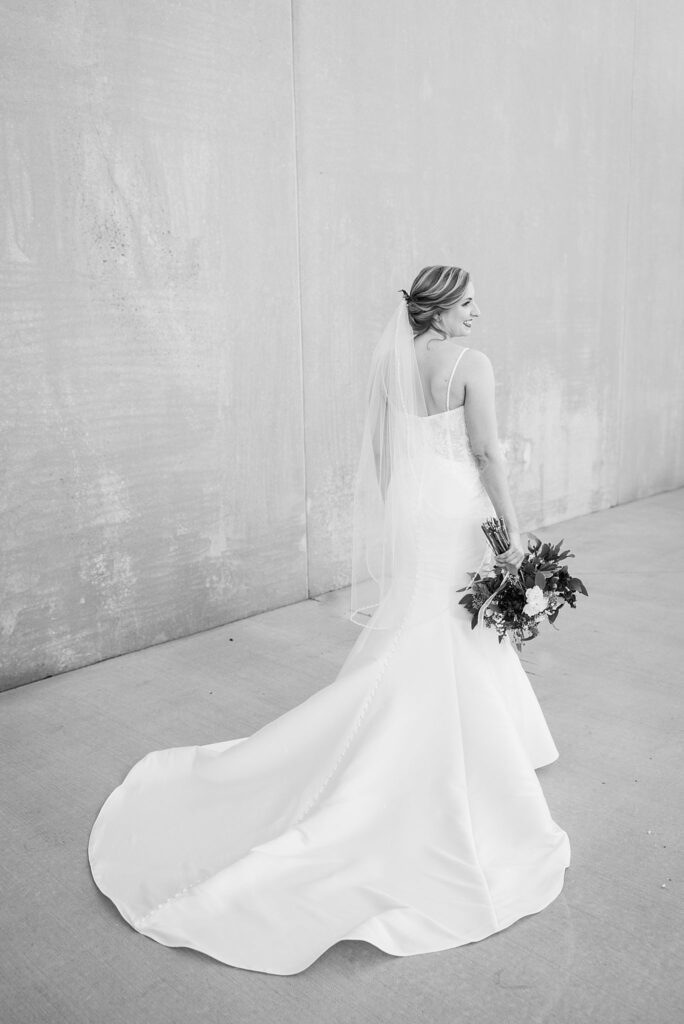 Captivating bride embraces her bridal bouquet, radiating elegance and joy at Judson Mill, downtown Greenville, South Carolina.