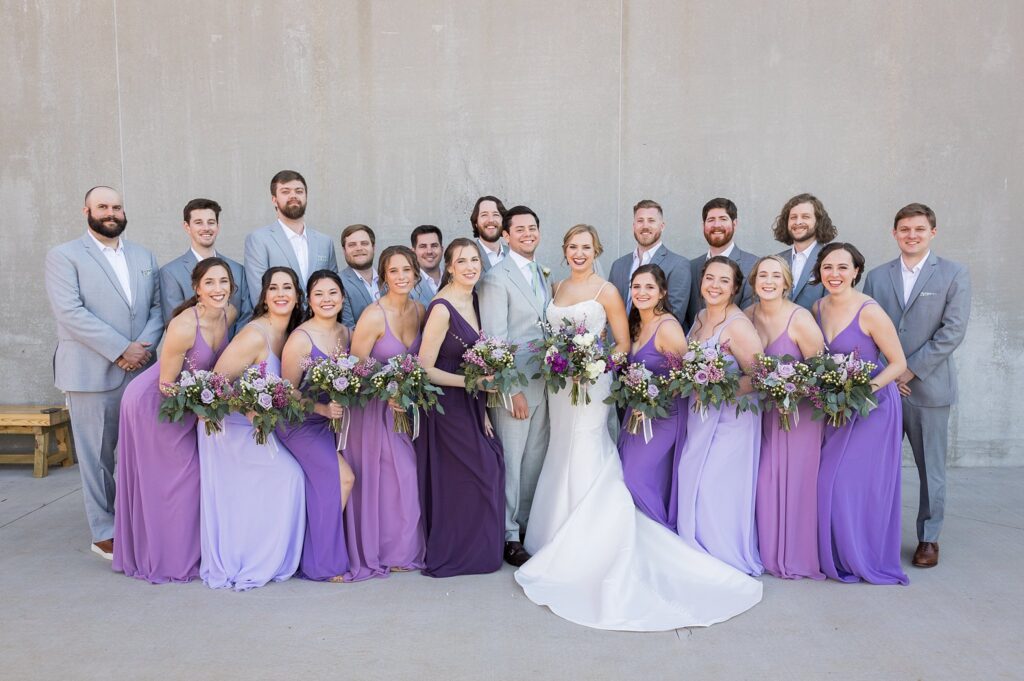 In this enchanting image, the bride and groom share a tender moment with their bridesmaids and groomsmen, celebrating their special day at the historic Judson Mill in downtown Greenville, South Carolina.