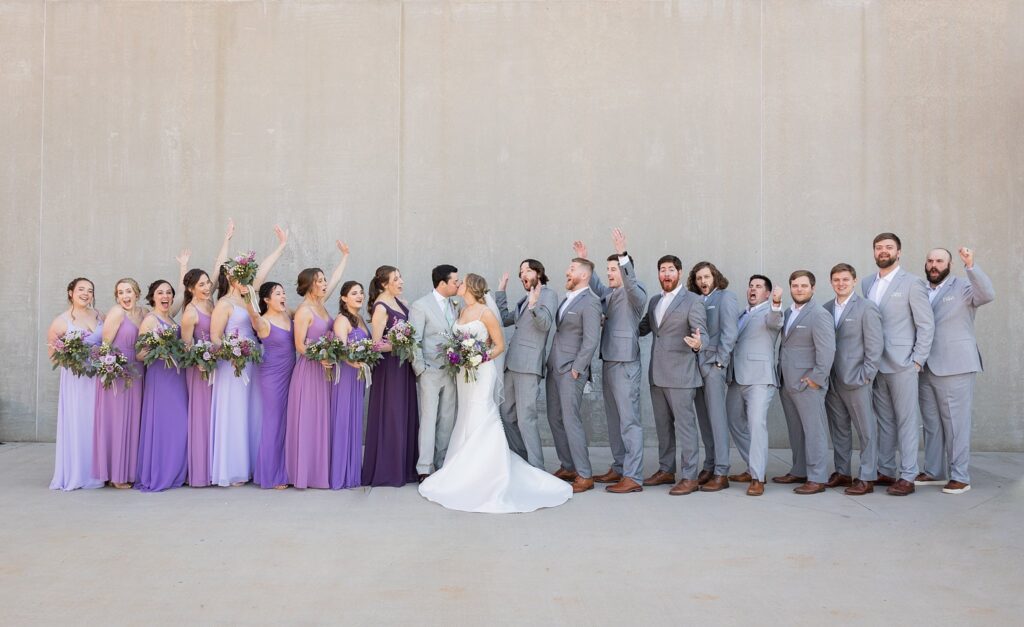 A stunning portrait of the bride and groom surrounded by their joyful bridesmaids and groomsmen at Judson Mill, downtown Greenville, South Carolina.