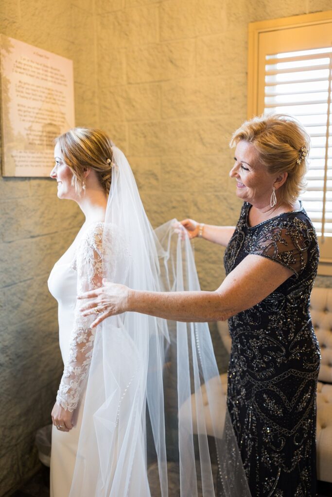 Bride's elegant moment as she puts on her earrings, beautifully captured by Lace + Honey