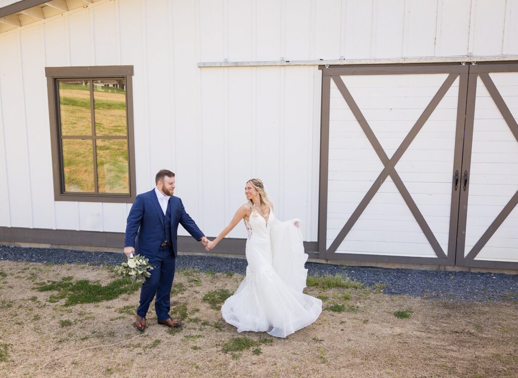 Romantic Stroll: Bride and Groom in Front of the Reception Barn at South Wind Ranch - Creating cherished memories on their wedding day