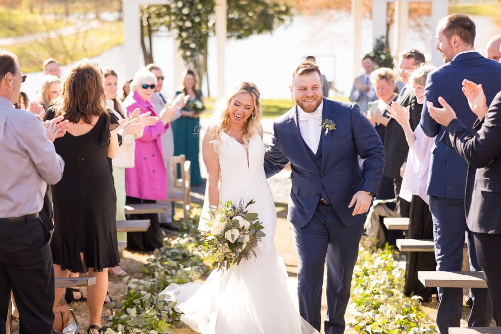 Newlywed Happiness: Bride and Groom's Cheery Exit from Their Ceremony - Embracing the celebration with smiles and laughter.